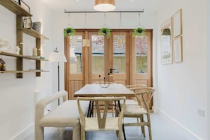 A dining area with a wooden table and chairs, a hanging light fixture, and a door with windows.