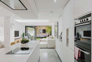 A modern kitchen with a central island, built-in appliances, and a view to an outdoor seating area.