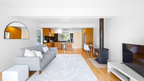A modern living room with a grey sofa, a flat-screen TV, and a fireplace. - Serene 2BR Retreat in Goughs Bay Lake Eildon (Goughs Bay)