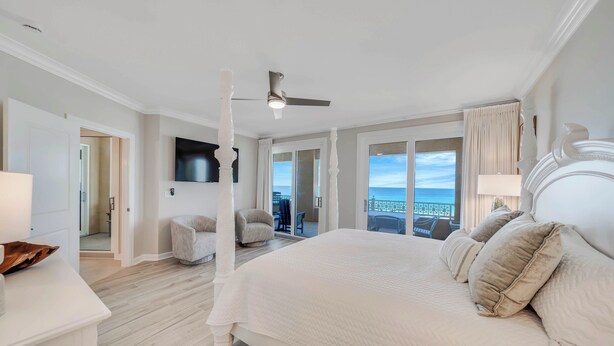 A spacious bedroom with a large bed, a ceiling fan, and a view of the ocean through large windows. - 4 BR En Soleil Directly on Gulf, 5th floor unit with the best views!! (Panama City Beach)