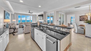 A spacious kitchen with a central island, white cabinetry, and a large window offering a view of the ocean. - 4 BR En Soleil Directly on Gulf, 5th floor unit with the best views!! (Panama City Beach)