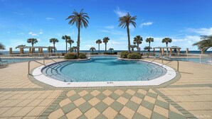 A large, clear swimming pool with a tiled deck, surrounded by palm trees and a white fence. - 4 BR En Soleil Directly on Gulf, 5th floor unit with the best views!! (Panama City Beach)