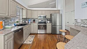 Une cuisine moderne avec des appareils en acier inoxydable, des meubles de couleur gris clair et un plancher en bois.