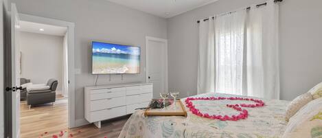 A bedroom with a bed, a TV, a desk, and a chair.
