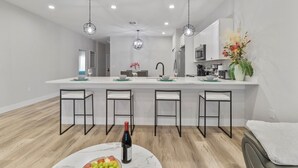 Una cocina moderna con una isla central, taburetes de bar e iluminación colgante.