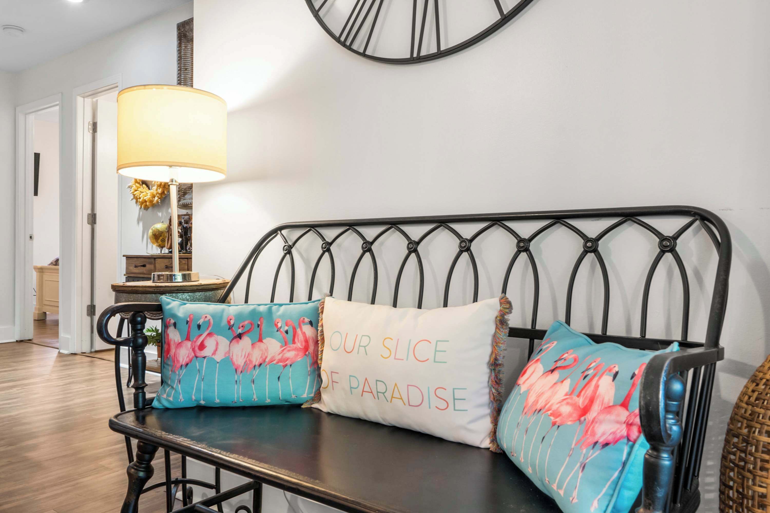 Ein Bett mit Kopfstück, zwei Kissen mit Flamingos und eine Lampe auf einem Nachttisch.