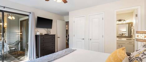 A bedroom with a bed, a dresser, a television, and a ceiling fan.