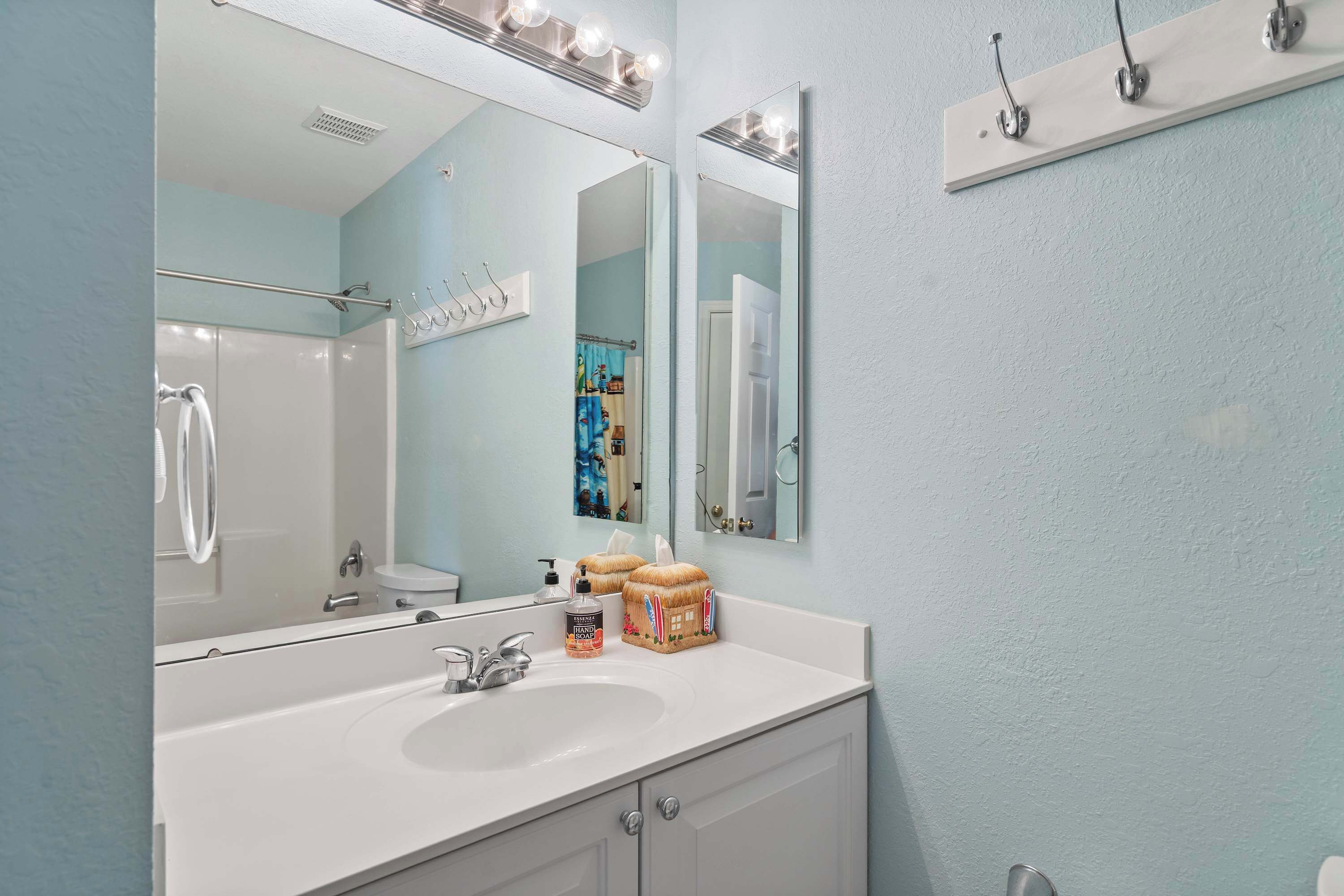 A bathroom with a white sink, a mirror, and a shower.