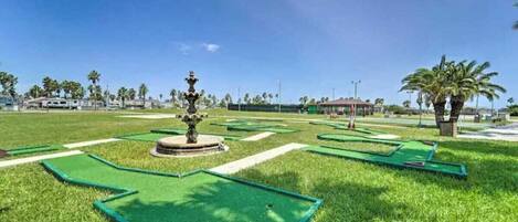 A golf course with green fairways, sand bunkers, and a central fountain.