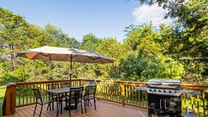 A deck with a grill, table, chairs, and an umbrella. - Peak Seasons at Massanutten (Mc Gaheysville)