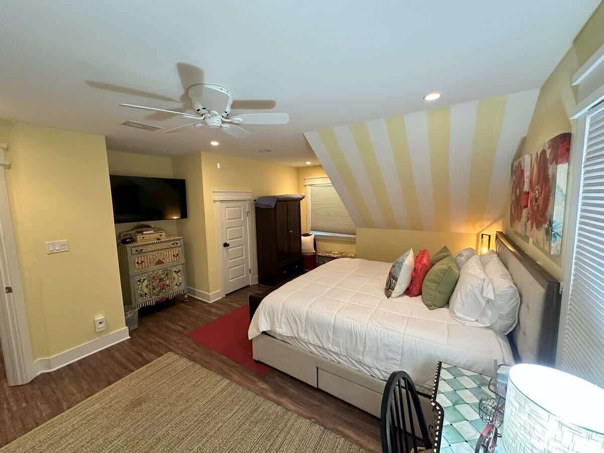 Un dormitorio con una cama, ventilador de techo, cómoda y televisor.