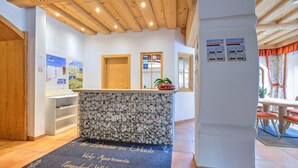 A reception area with a stone counter, wooden ceiling, and a welcome mat. - Bright Vicky Apartment With Infrared Sauna (Wildschönau)