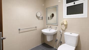 A bathroom with a toilet, sink, and mirror.