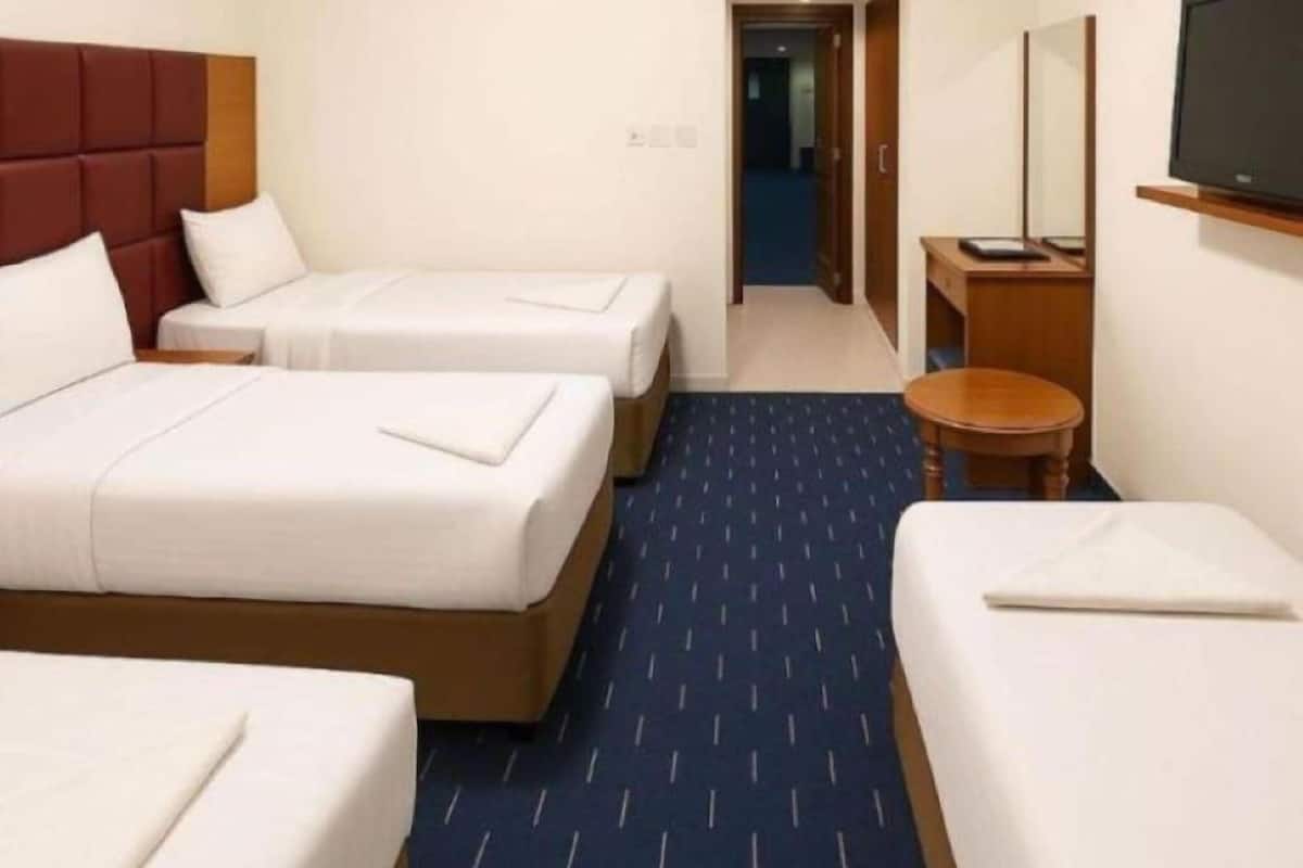 Ein Hotelzimmer mit zwei Betten, einem Fernseher und einem kleinen Tisch.