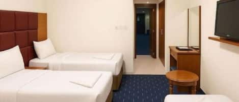 A hotel room with two beds, a TV, and a small table.