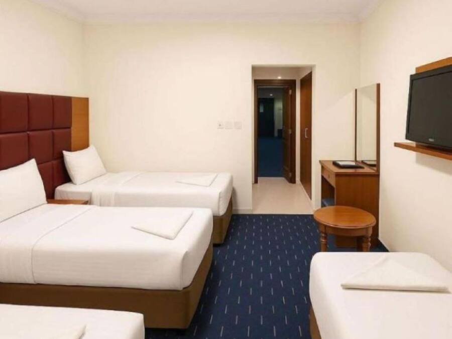Una habitación de hotel con dos camas, un televisor y una mesita.