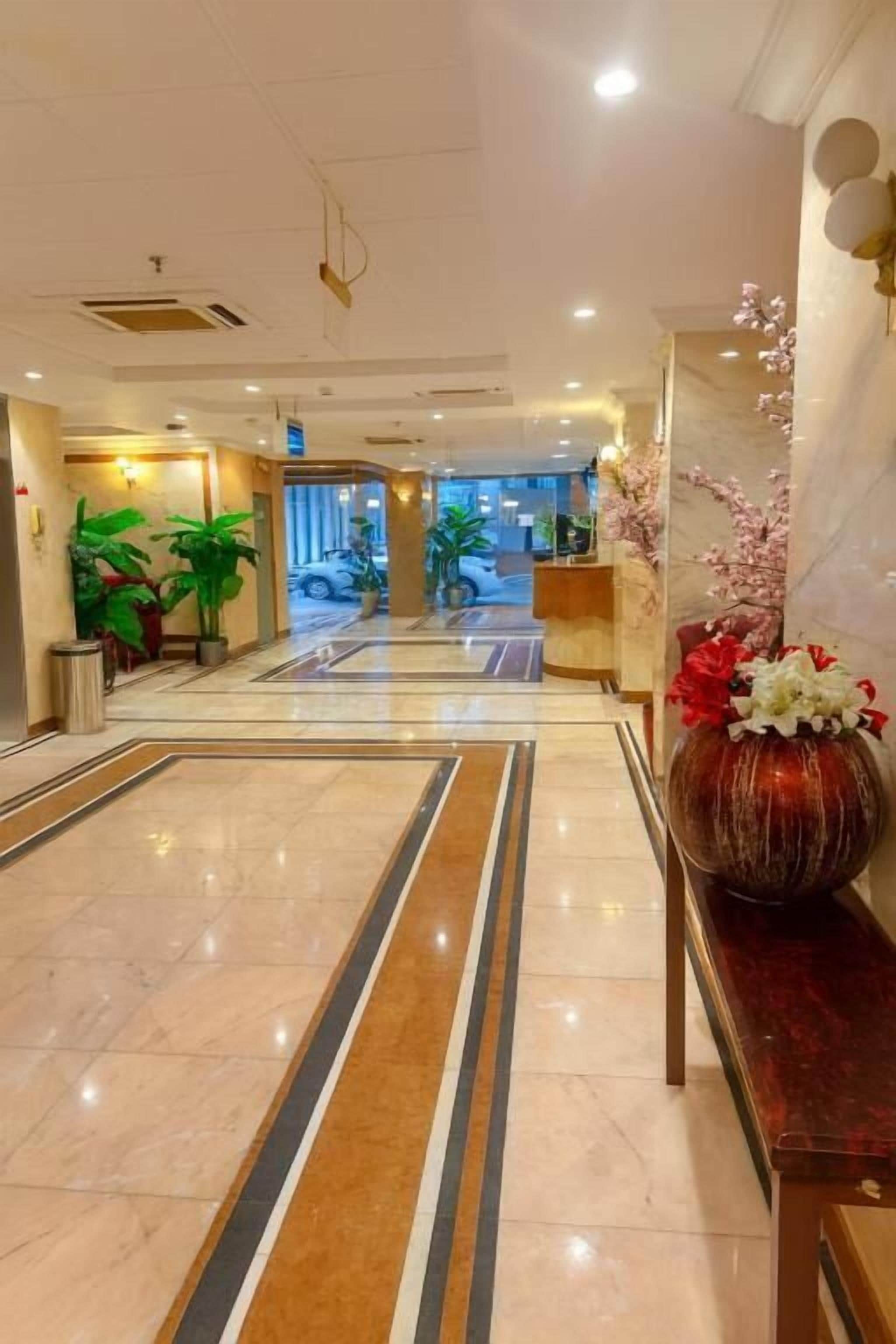 Un vestíbulo de hotel con piso pulido, una recepción y plantas en macetas.