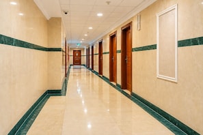 A hotel corridor with a marble floor, wooden doors, and green marble borders. - Jawaher Al Bait 2 Hotel Makkah by oteleia (Makkah)