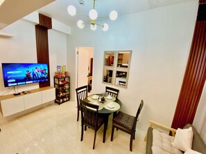 Ein modernes Wohnzimmer mit Flachbildfernseher, Esstisch, Stühlen und einer Couch.
