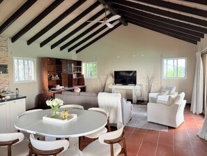 A spacious living room with a dining area, a TV, and a fireplace. - 5BR Hilltop Villa! Pool & Ocean Views (Sint Maarten)