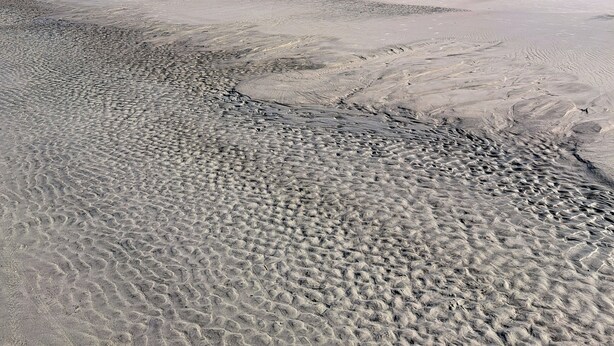 A wide sandy beach with a clear blue sky.