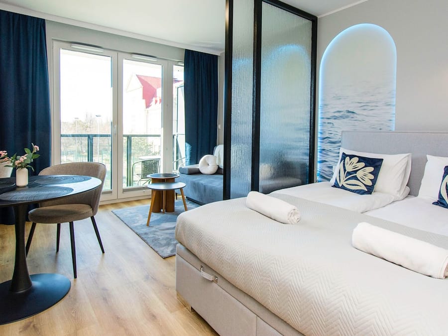Habitación de hotel moderna con cama, escritorio y silla. Se ve el exterior a través de amplios ventanales.