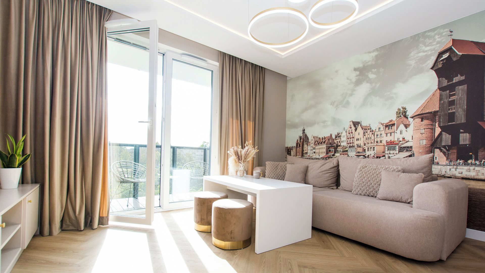 Una sala de estar moderna con un sofá, una mesa de centro y vistas a un paisaje urbano a través de un ventanal.