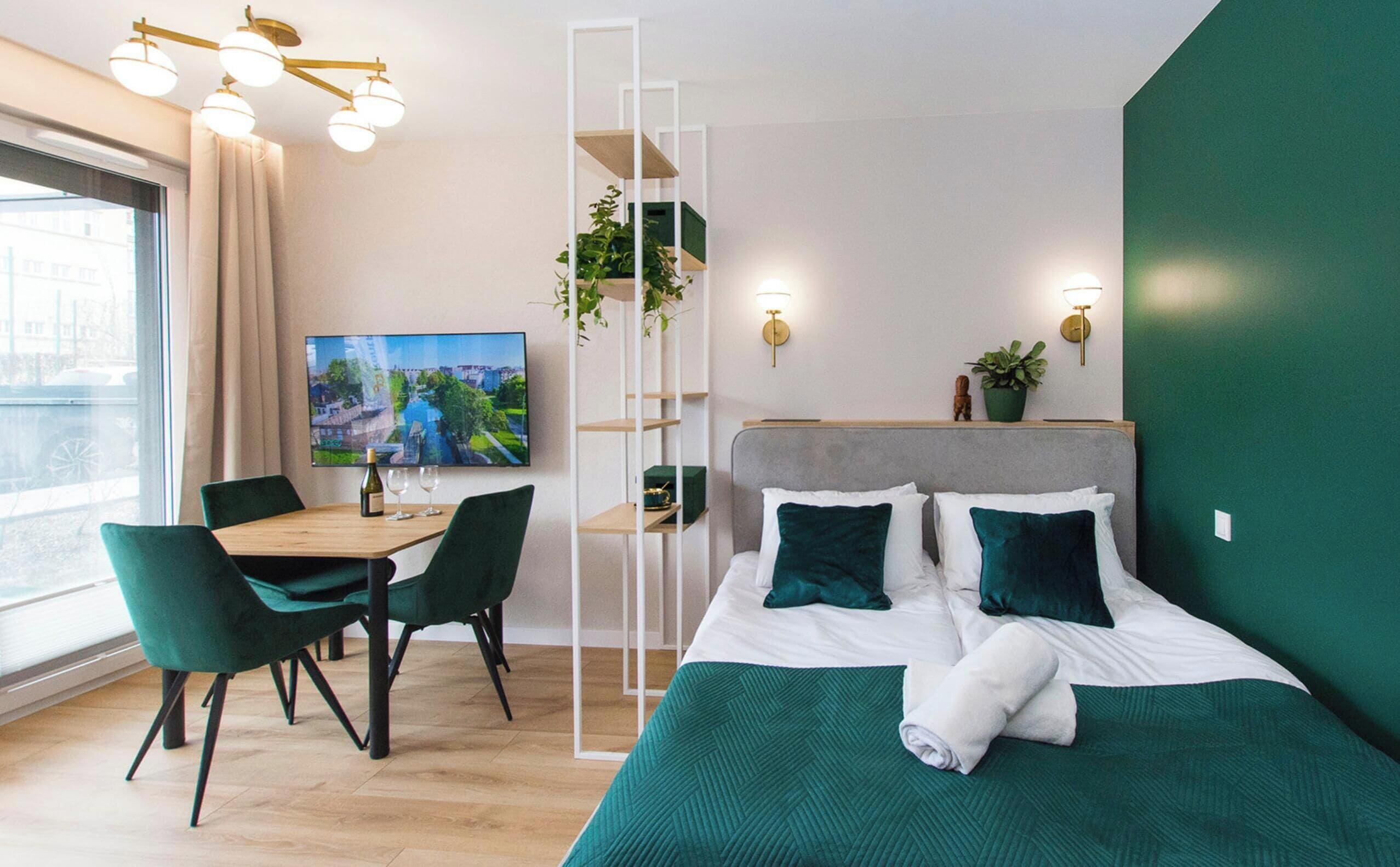 Une chambre d’hôtel moderne équipée d’un lit, d’une table à manger avec des chaises, d’un téléviseur et offrant une vue sur la ville.
