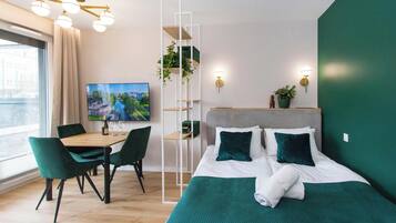 Une chambre d’hôtel moderne équipée d’un lit, d’une table à manger avec des chaises, d’un téléviseur et offrant une vue sur la ville.