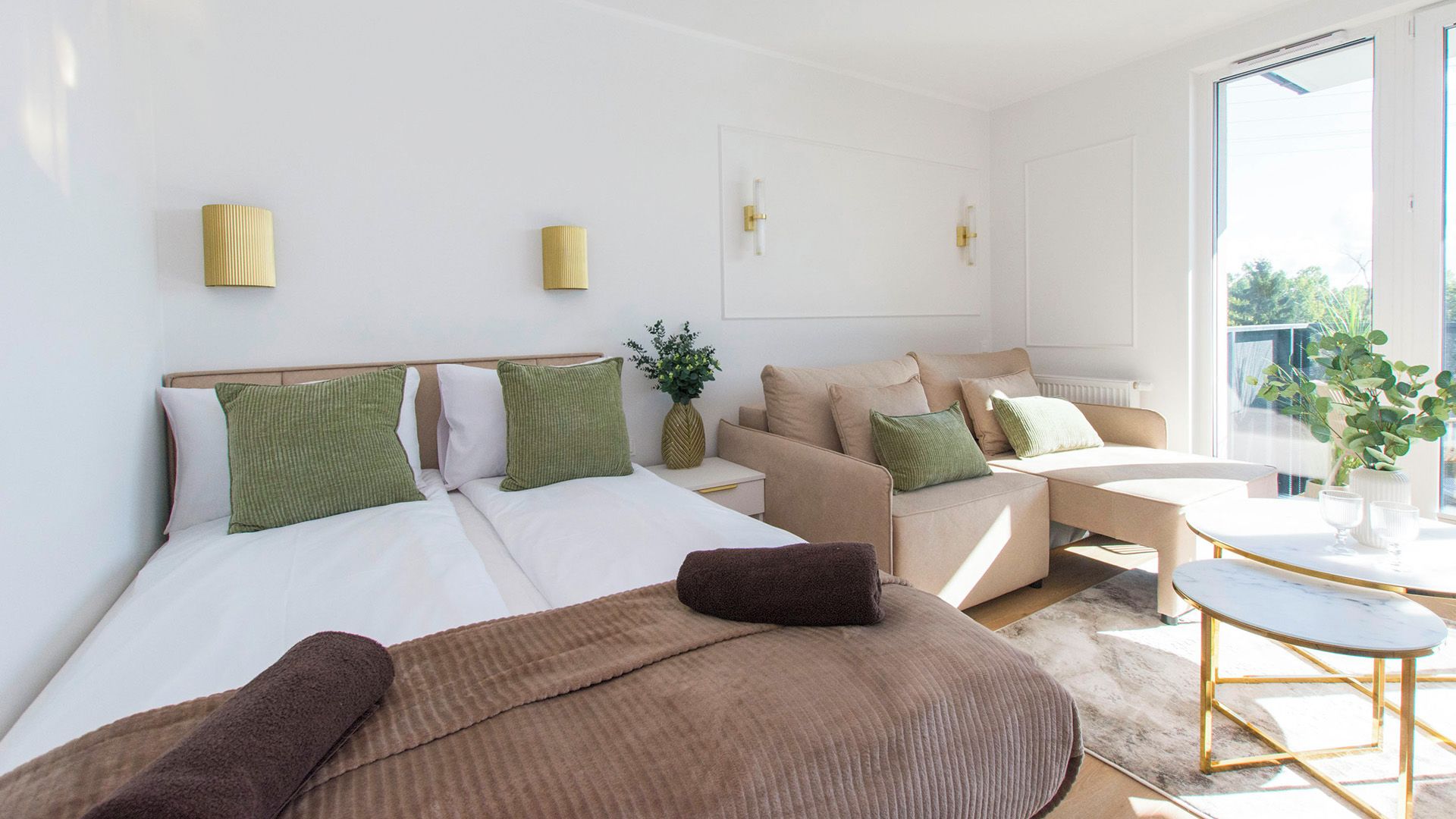 Habitación de hotel moderna con una cama grande, un sofá, una mesita y vistas al exterior.