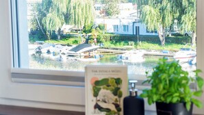 Blick auf einen Hafen mit vertäuten Booten, umgeben von Grünflächen und Gebäuden.