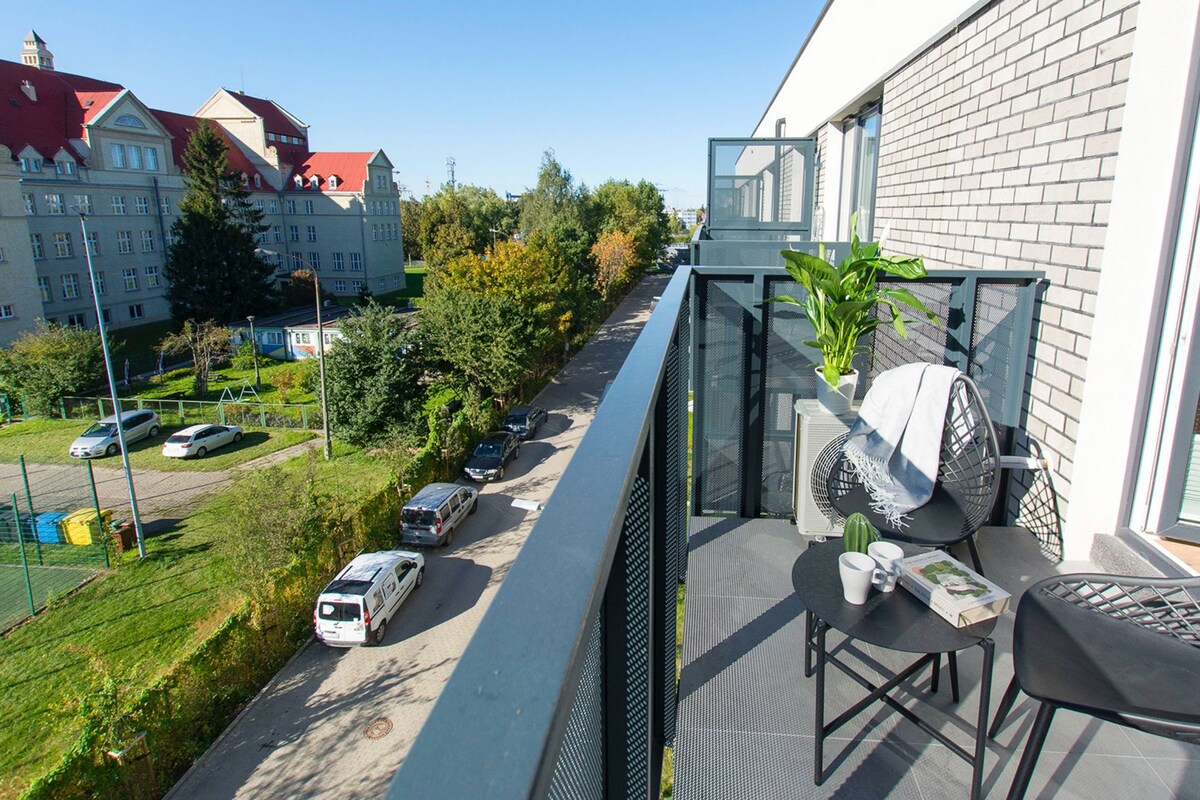 Ein Balkon mit Stuhl, Topfpflanze und Tisch, auf dem ein Buch und eine Tasse stehen.