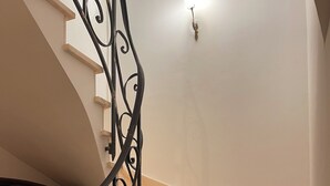 Eine Marmortreppe mit aufwendig gestalteten schwarzen Metallgeländern, die zu einer Empore führt.