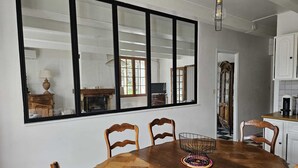Ein Essbereich mit großem Fenster, Holzsesseln, einem Holztisch und einer Chandelier.