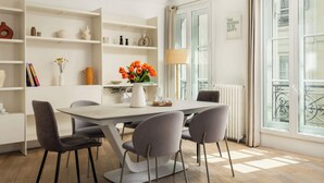 Un coin repas comprenant une table, des chaises, un vase de fleurs et une bibliothèque.