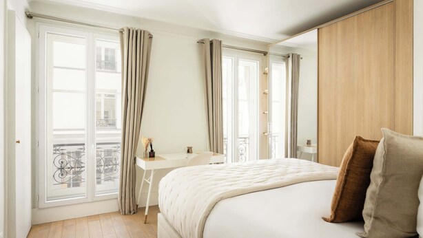 Une chambre avec un lit, un bureau et une vue sur l’extérieur.
