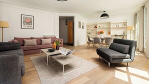 Un salon moderne avec un canapé, un fauteuil, une table basse et des lampes suspendues.