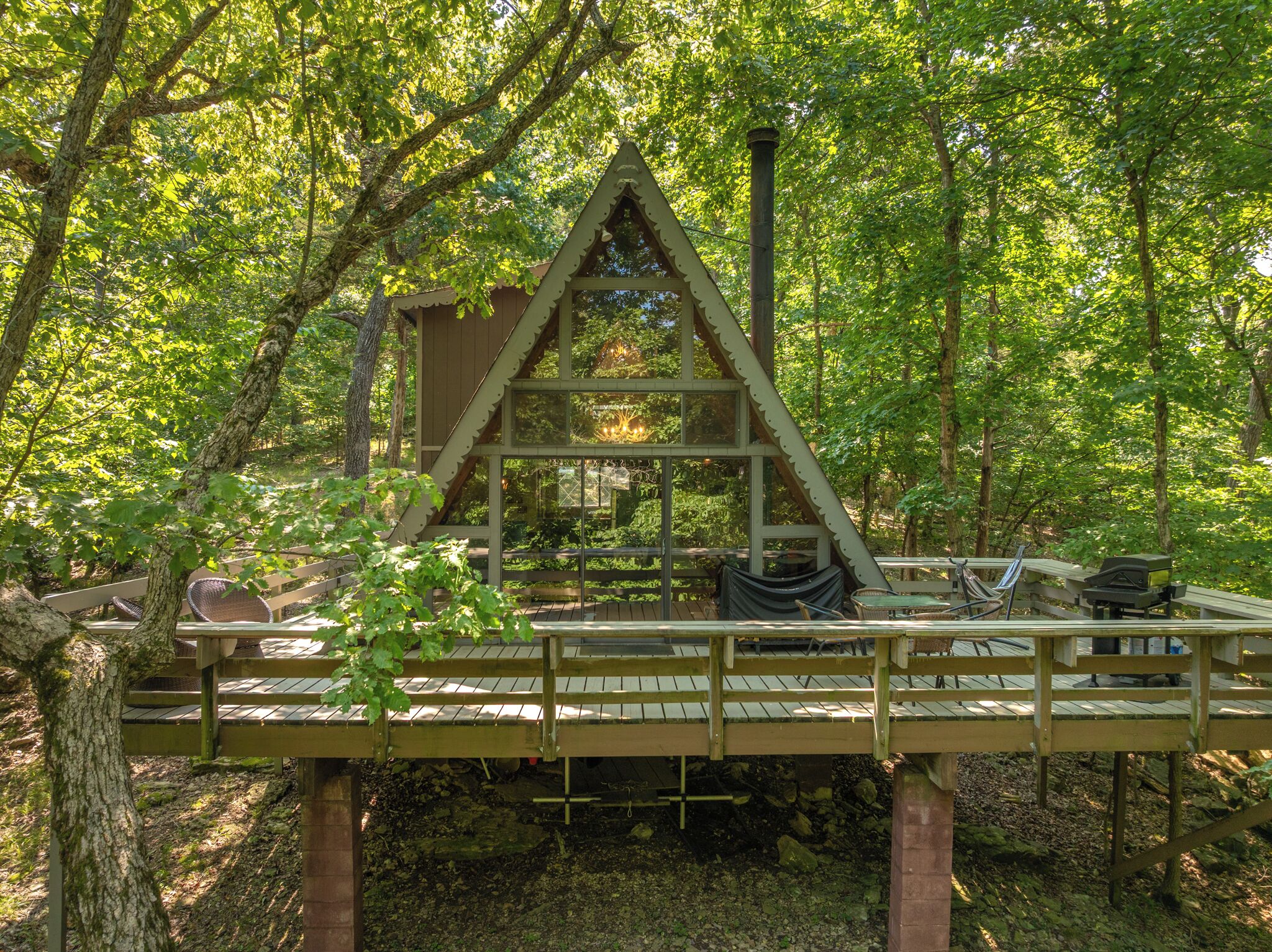 A wooden deck with a triangular viewing platform, surrounded by trees.