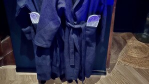 Two dark blue robes hanging on a rack in a room with a patterned floor and a blue wall. - La traversière the secrets of desire (Villeneuve-sur-Lot)