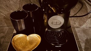 A coffee maker, black cups, a heart-shaped object, and a drawer with books and a teapot. - La traversière the secrets of desire (Villeneuve-sur-Lot)