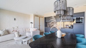 Una sala moderna con una mesa de comedor negra, sofás blancos y sillas color turquesa.