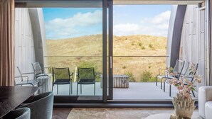 Una habitación moderna con un amplio ventanal corredero que da a un patio exterior. En el interior, hay una mesa de comedor con sillas, un sofá y un jarrón decorativo.