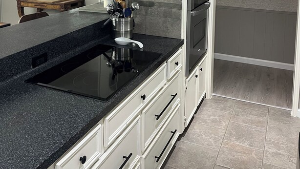 Una cucina moderna con un piano di lavoro in granito nero, elettrodomestici in acciaio inossidabile e un'ampia finestra con persiane.