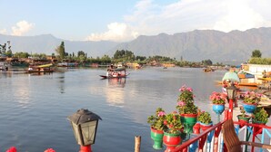 A riverside view with boats, potted plants, and a wooden railing. - Chicago Houseboats  (Srinagar)