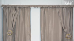Quarto com duas cortinas amarradas, revelando uma janela.