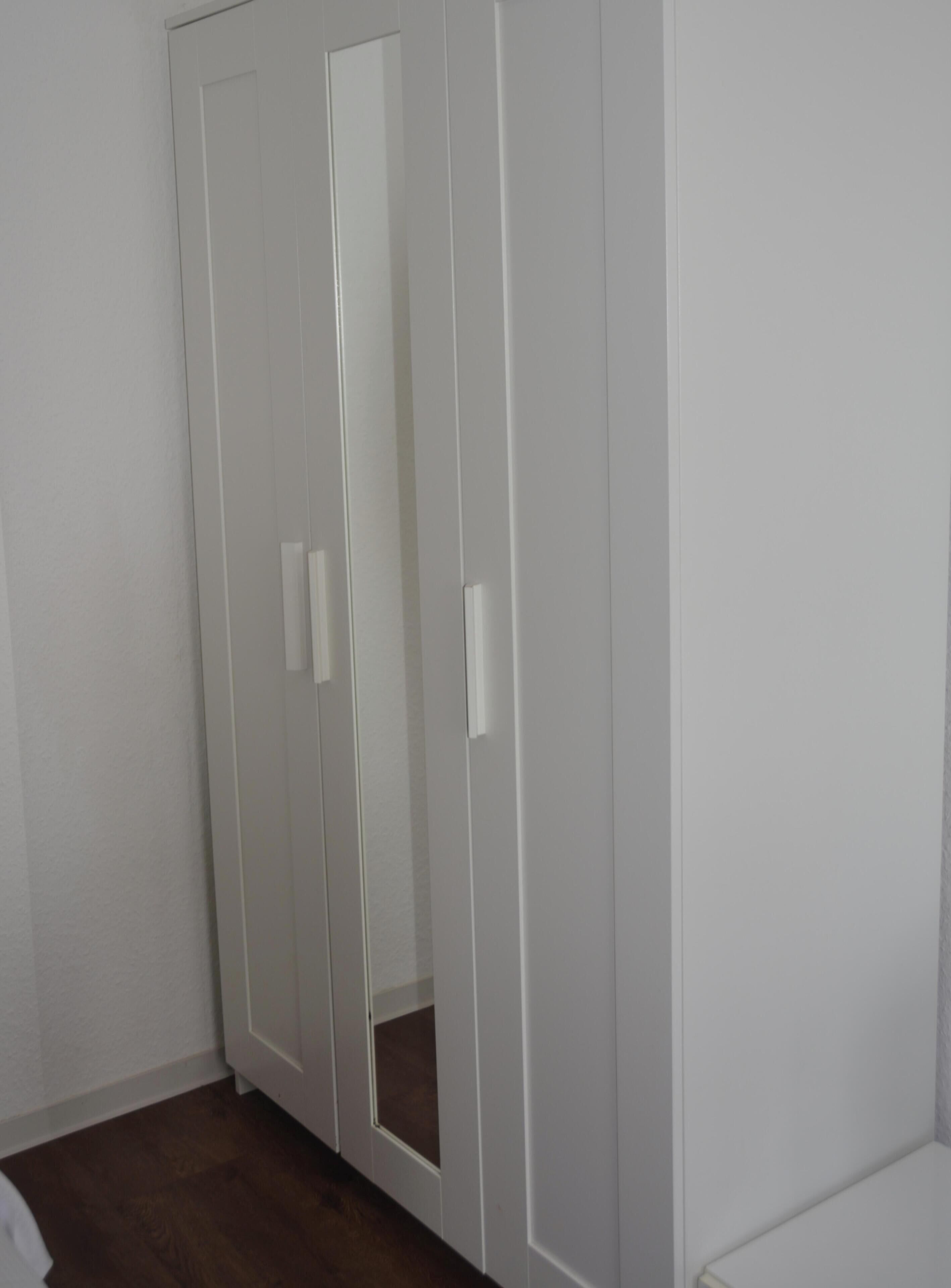 Un armario blanco con puertas espejadas y tiradores.