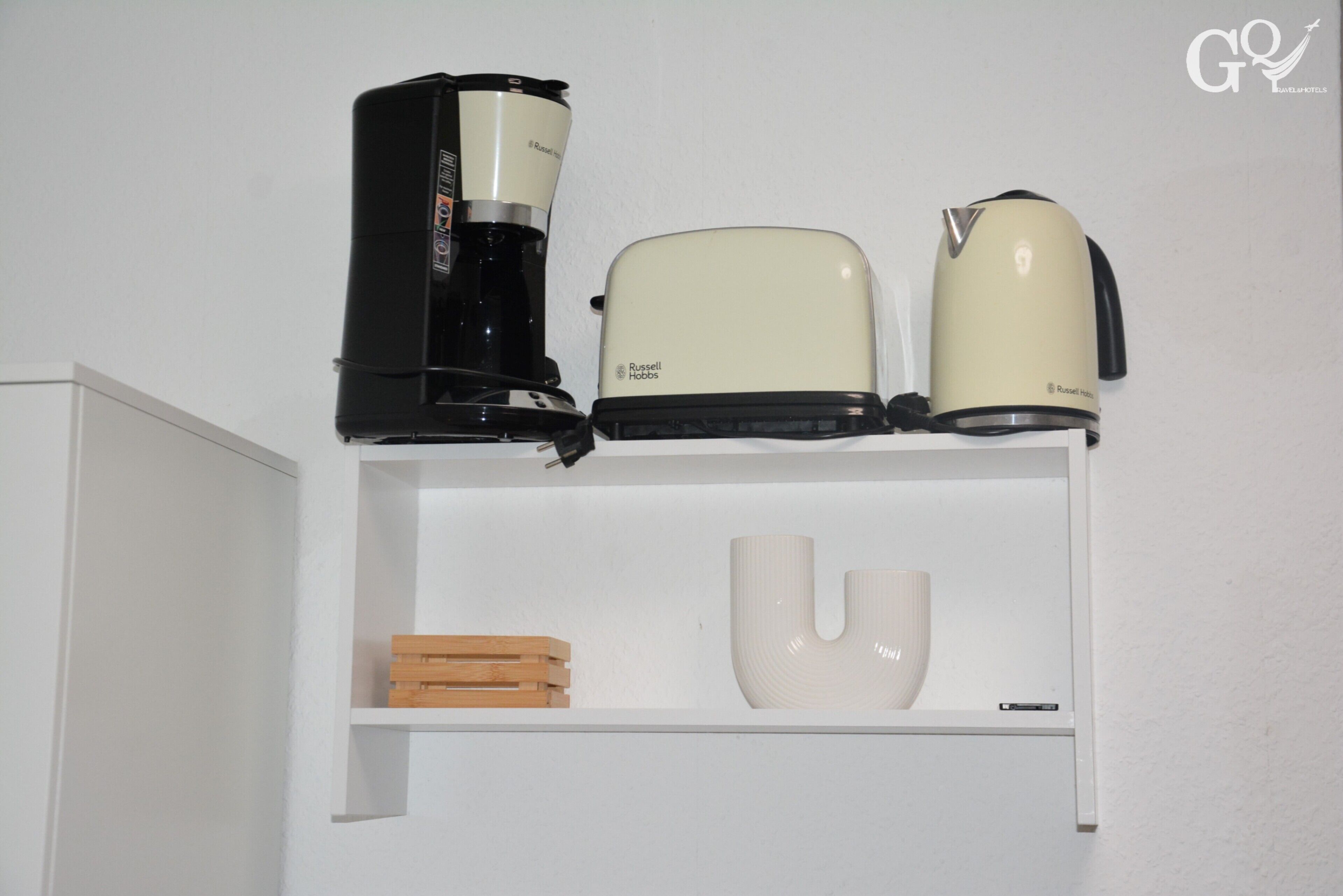 A white shelf with a coffee maker, a toaster, and a kettle.