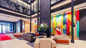 Eine moderne Lobby mit rotem Teppich, einer Sitzecke und einem farbenfrohen Wandbild.