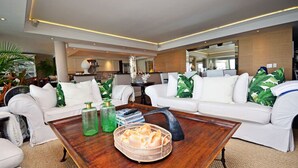 A modern living room with white sofas, a wooden coffee table, and green decorative pillows.