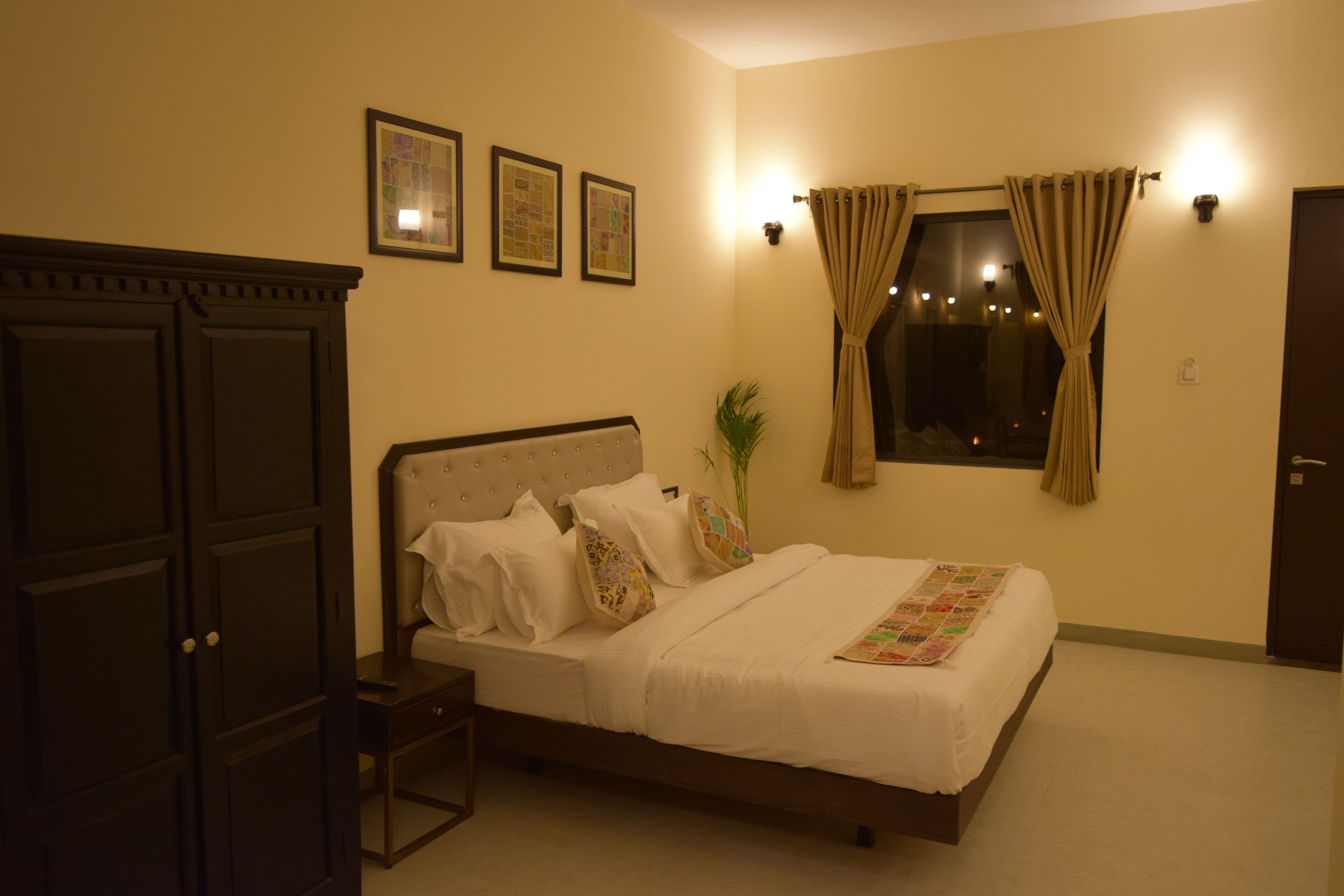 Un dormitorio ordenado con cama, mesita de noche, armario y ventana con cortinas.
